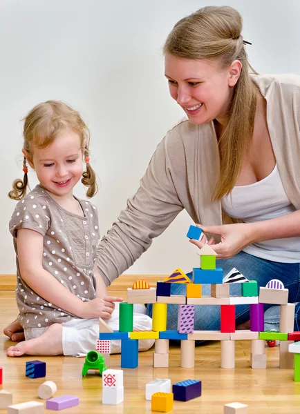 Petite fille et jeune femme s'amusent à jouer avec des blocs de construction sur le — Photo