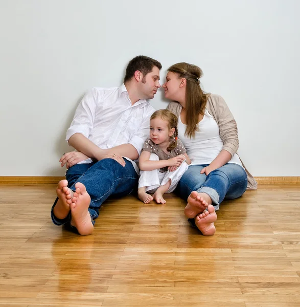 벽에 바닥에 앉아 행복 한 가족 — 스톡 사진