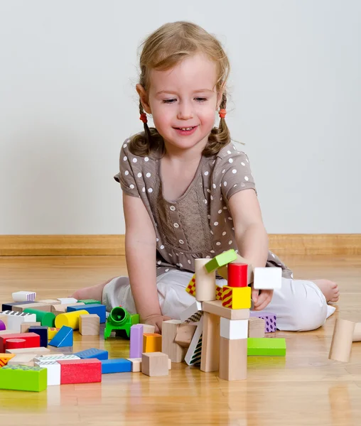 Carino bambina seduta sul pavimento e giocare con i blocchi di costruzione Immagini Stock Royalty Free