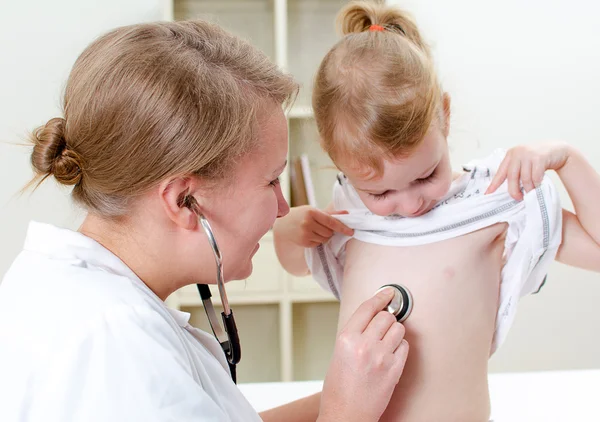 Женщина-врач осматривает маленькую девочку стетоскопом — стоковое фото