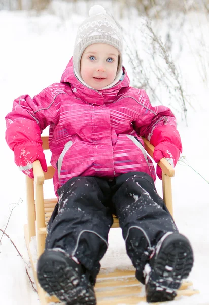 Nettes kleines Mädchen sitzt im Schlitten im Park — Stockfoto