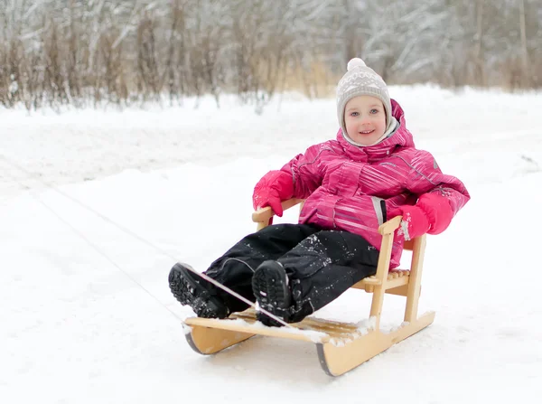 Cute little girl sitting in sled in the park — Stock Photo, Image