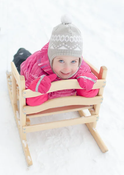 Portrait of cute little girl sitting in sled — Stock Photo, Image