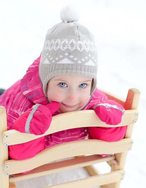 Kızak içinde oturan sevimli küçük kız portresi — Stok fotoğraf