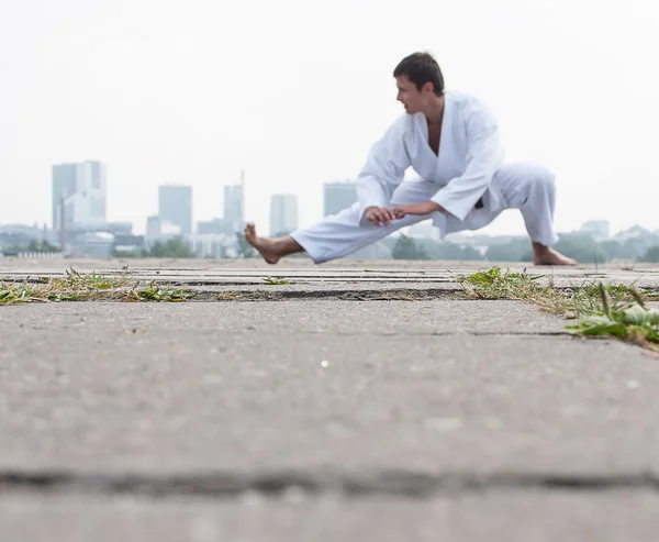 Giovane maestro di karate che fa esercizio n la mattina sullo sfondo della città — Foto Stock