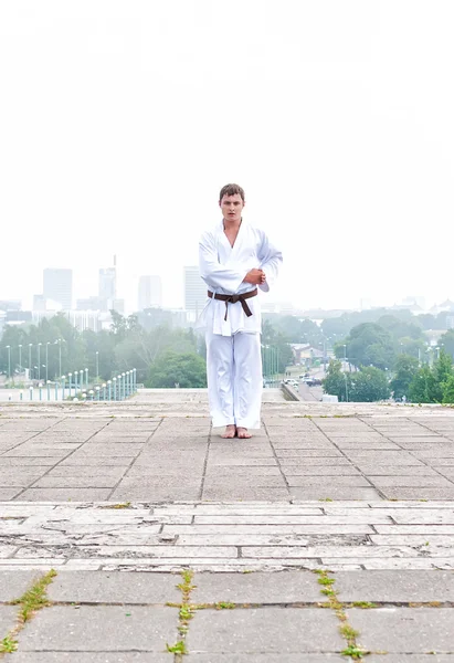 Giovane maestro di karate che fa esercizio n la mattina sullo sfondo della città — Foto Stock
