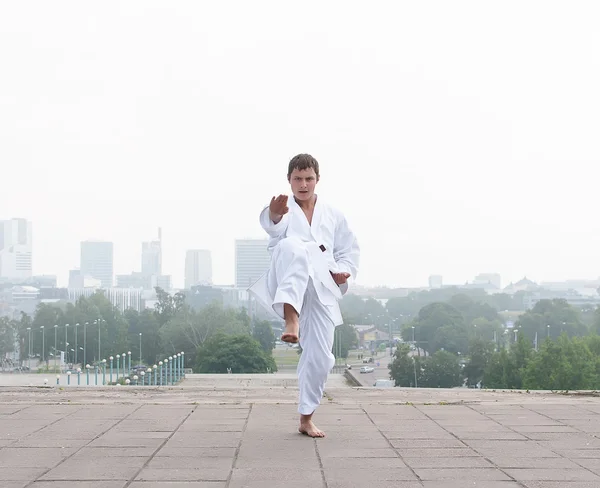 Junger Karate-Meister beim morgendlichen Training vor Stadtkulisse — Stockfoto