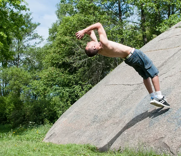 Mladý muž dělá salto venku — Stock fotografie