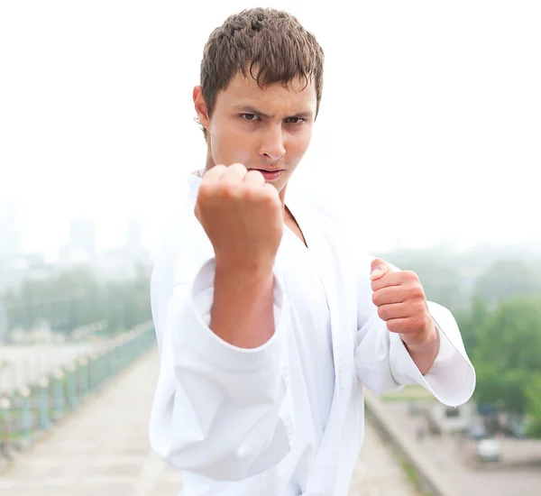 Jonge karate meester doen oefening n de ochtend op stad achtergrond — Stockfoto