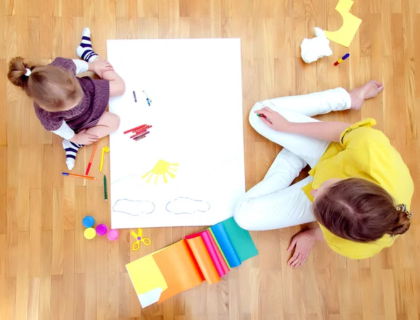 Young woman and little girl drawing together sitting on the floor. Top view — Stock Photo, Image