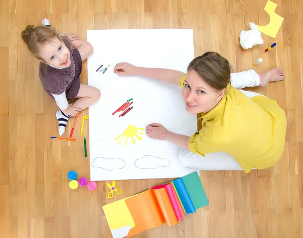 Young woman and little girl drawing together sitting on the floor. Top view. — Stock Photo, Image