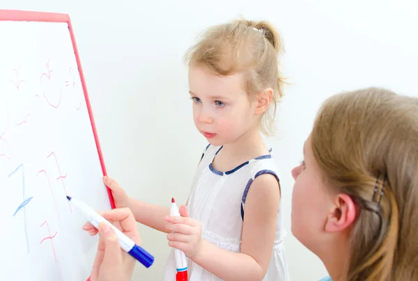 Jolie petite fille avec professeur près du tableau blanc — Photo