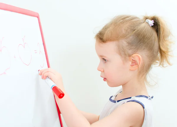 Bella bambina che scrive con un pennarello rosso su una lavagna bianca — Foto Stock