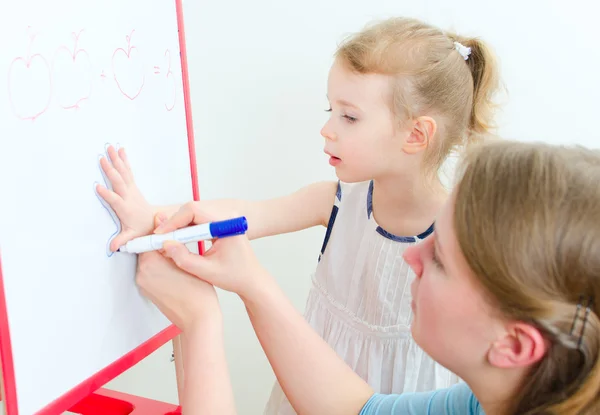 Pretty little girl with teacher near whiteboard — Stock Photo, Image