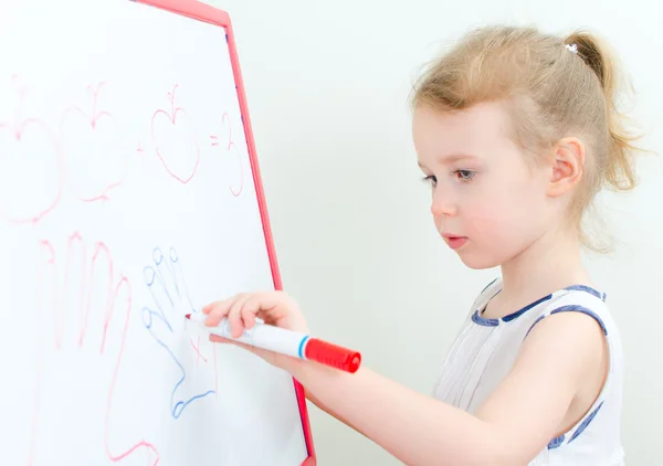 Hübsches kleines Mädchen schreibt mit rotem Filzstift auf ein Whiteboard — Stockfoto