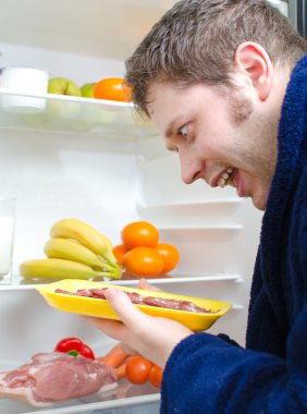 hombre guapo va a comer jamón cerca abre el refrigerador