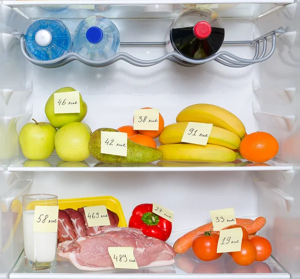 Nevera abierta llena de frutas, verduras y carne con calorías marcadas —  Fotos de Stock