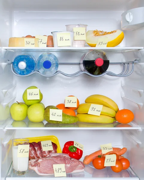 Открытый холодильник, полный фруктов, овощей и мяса с отмеченными калориями — стоковое фото