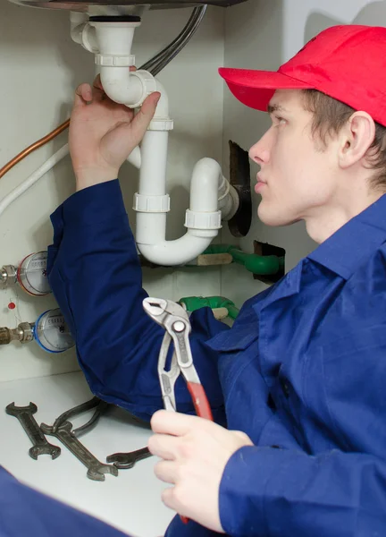 Plumber in uniform repairing pipeline in the house. — Stock Photo, Image