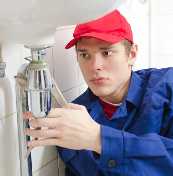 Fontanero en uniforme reparando oleoducto viejo en la casa . — Foto de Stock