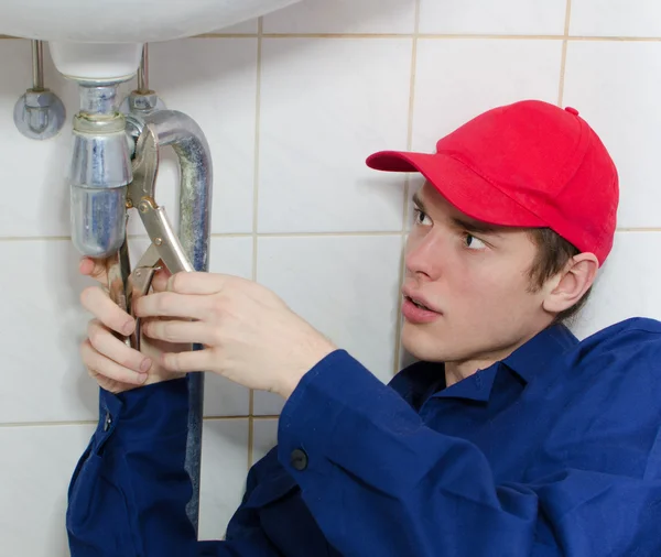 Fontanero en uniforme reparando oleoducto viejo en la casa . — Foto de Stock