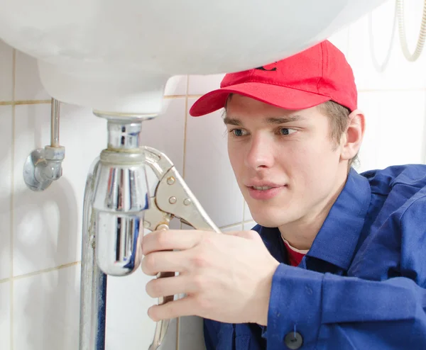 Plumber in uniform repairing old pipeline in the house. — Stock Photo, Image