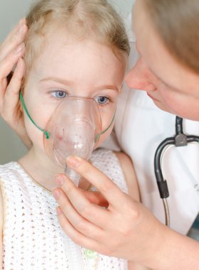 Doktor inhalasyon için küçük kız yardımcı olur.
