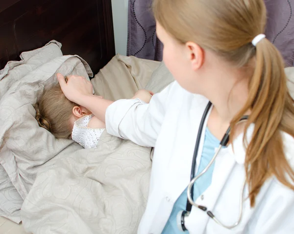 Вид сверху больного ребенка, лежащего в постели и посещающего врача — стоковое фото