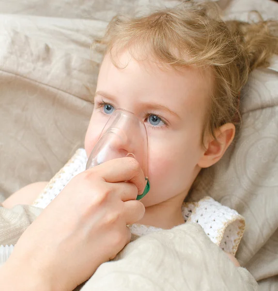 Porträt eines kleinen Mädchens, das mit Inhalator-Maske im Bett liegt — Stockfoto