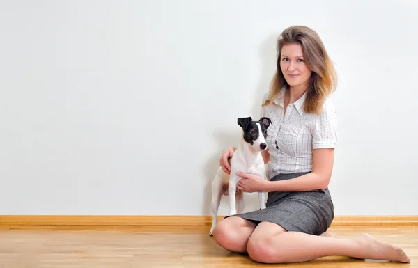 Jovem mulher e seu lindo cão sentado contra a parede — Fotografia de Stock