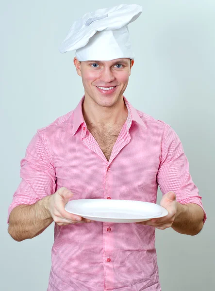 Молодой красивый шеф-повар держит пустую тарелку — стоковое фото