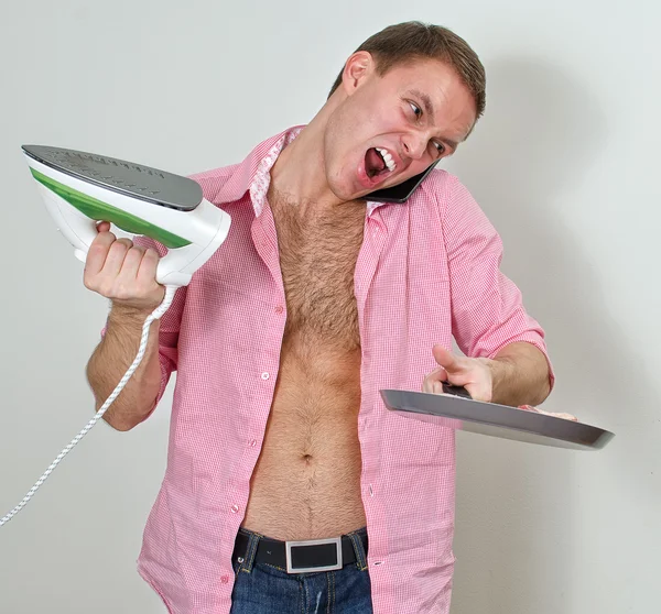 Young man with pan and iron speaking on the phone — Stock Photo, Image