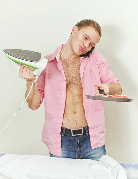 Young man with pan and iron speaking on the phone — Stock Photo, Image