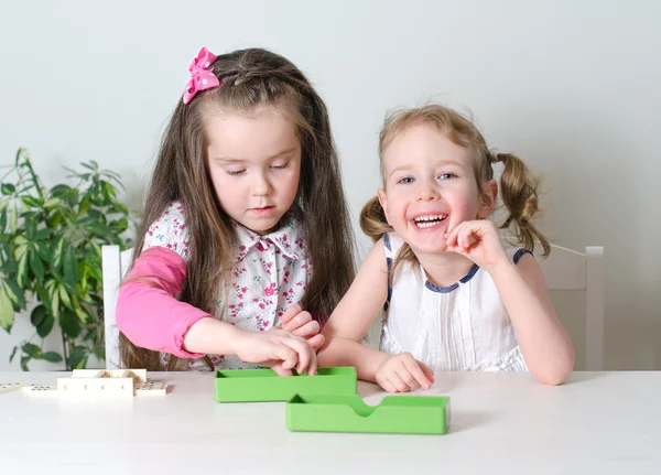 Två små flickor spelar domino på bordet — Stockfoto