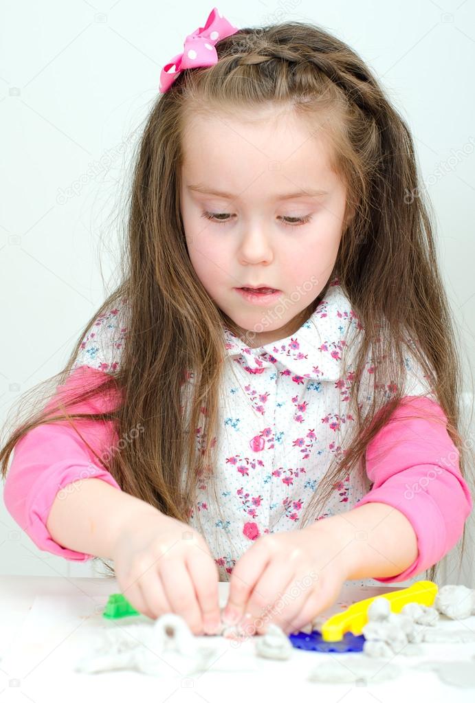Cute undistracted girl sculpting using clay