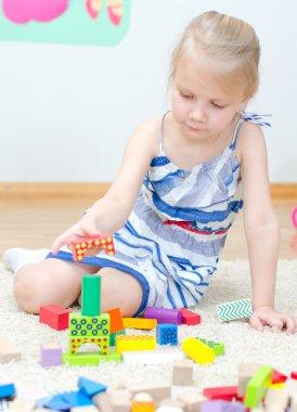 katta oturan ve yapı taşları ile oynarken sevimli küçük kız
