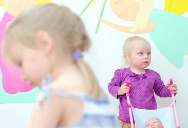 Baby girl with buggy in kindergarten — Stock Photo, Image