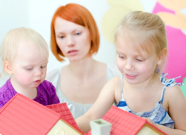 Crianças e sua mãe brincando com a casa de bonecas — Fotografia de Stock