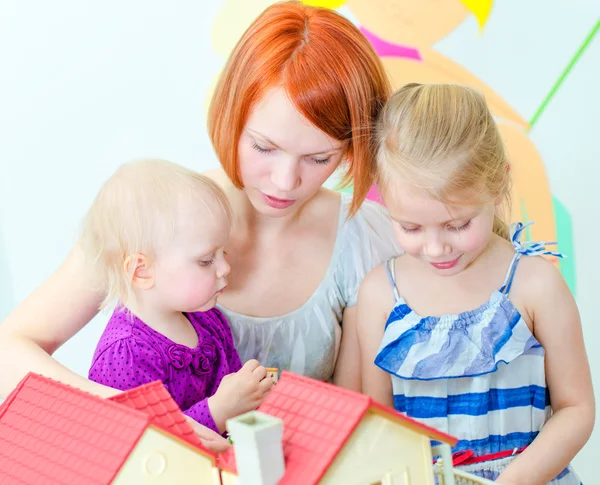 Kinderen en hun moeder spelen met dollhouse — Stockfoto