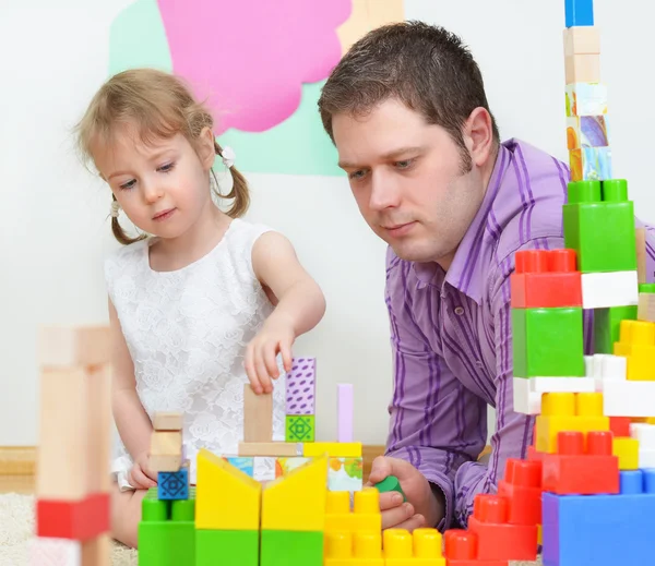 Far och dotter leker med färgade block. — Stockfoto