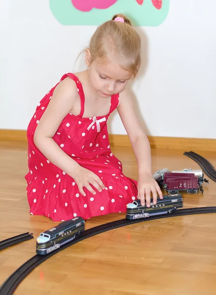 Κοριτσάκι παίζει με σιδηροδρομικού κάθεται στο πάτωμα — Φωτογραφία Αρχείου
