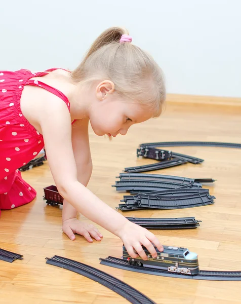 Liten flicka spelar med järnväg sitter på golvet — Stockfoto