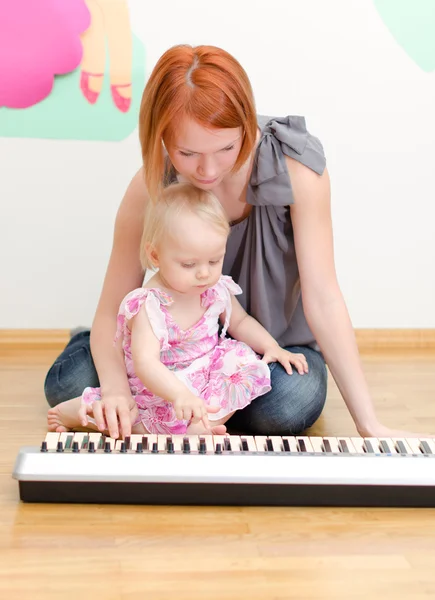 Klein meisje en haar moeder piano spelen — Stockfoto