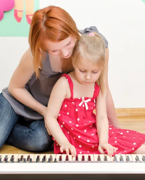 Liten flicka och hennes mamma spelar piano — Stockfoto
