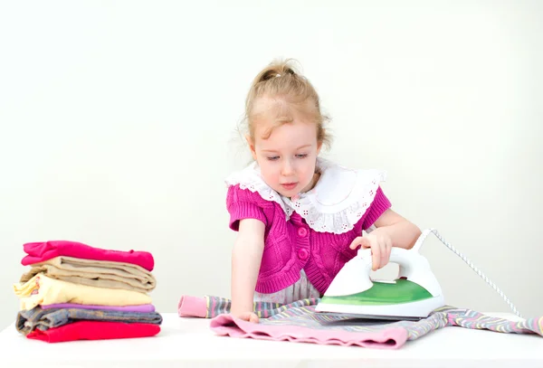 Schattige kleine meisje strijken kleding — Stockfoto