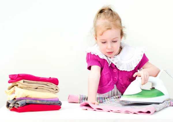 Niedliches kleines Mädchen bügelt Kleidung — Stockfoto