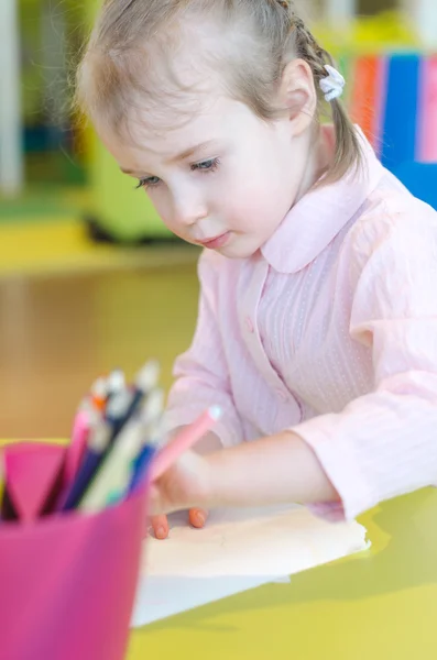 Klein meisje is tekenen met pen in voorschoolse — Stockfoto