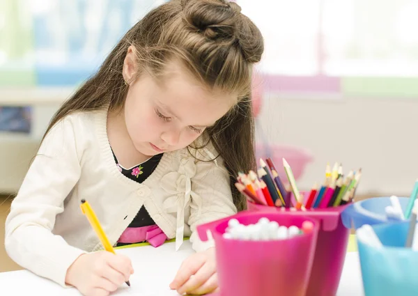 Маленькая девочка рисует ручкой в детском саду — стоковое фото
