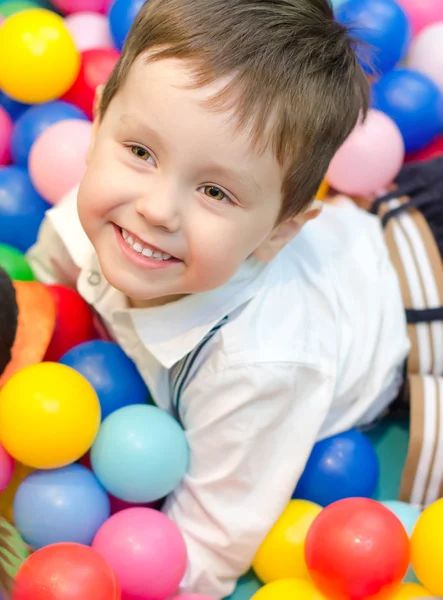 Счастливый маленький мальчик, сидящий на ярких шарах — стоковое фото