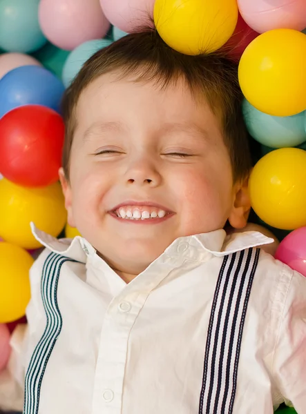 Leende liten pojke ligga i färgglada bollar — Stockfoto